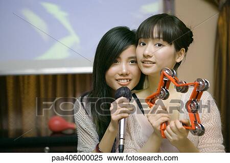 Two young women singing karaoke View Large Photo Image Stock Photography - Two young women singing karaoke. Fotosearch