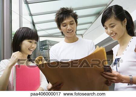 Young adults looking at unrolled documents View Large Photo Image Stock Photo - Young adults looking at unrolled documents. Fotosearch