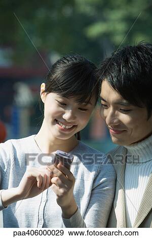 Young couple using cell phone together View Large Photo Image Stock Photo - Young couple using cell phone together. Fotosearch