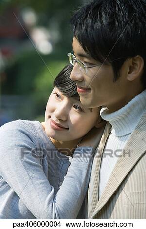 Picture - Young couple, woman leaning head on man's shoulder, both looking away. Fotosearch
