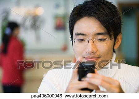 Young man looking at cell phone, smiling View Large Photo Image Stock Photograph - Young man looking at cell phone, smiling. Fotosearch