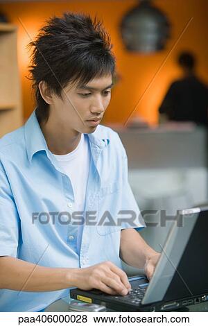 Young man using laptop View Large Photo Image Stock Photo - Young man using laptop. Fotosearch