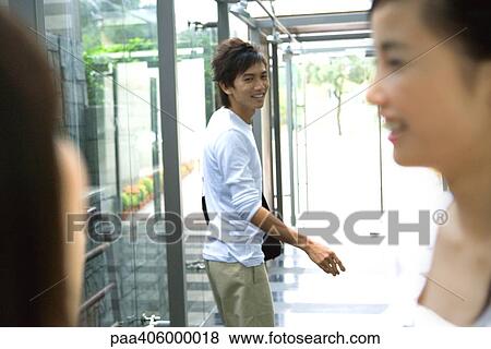 Stock Photo - Young man walking away from friends. Fotosearch