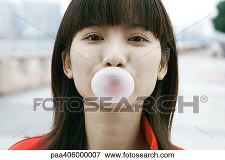 Stock Photo - Young woman blowing bubble, close-up. Fotosearch