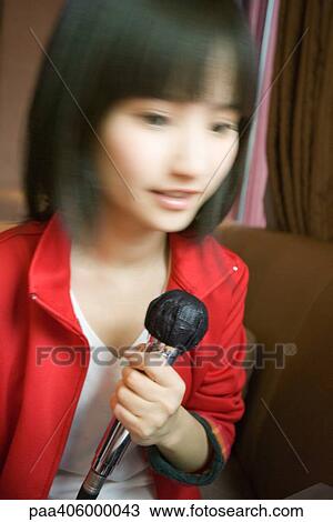 Young woman holding microphone, blurred motion View Large Photo Image Stock Image - Young woman holding microphone, blurred motion. Fotosearch