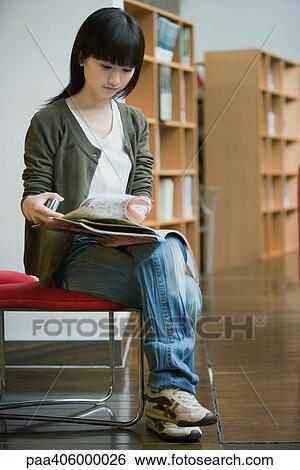 Stock Photograph - Young woman studying in library. Fotosearch