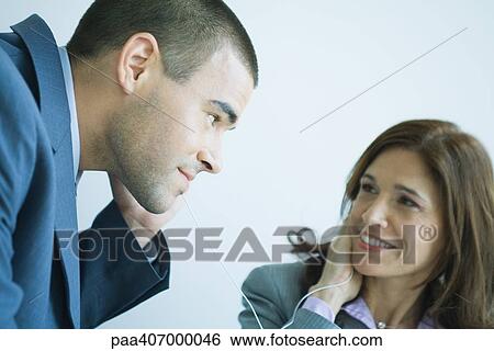 Business colleagues sharing earphones View Large Photo Image Stock Photograph - Business colleagues sharing earphones. Fotosearch