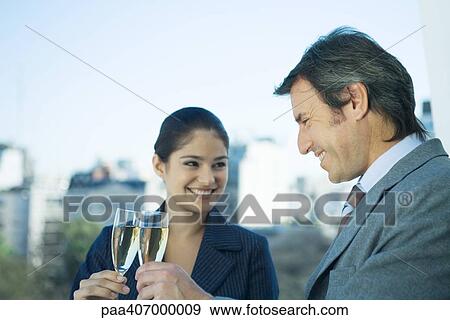 Businessman and young female associate toasting with glasses of champagne View Large Photo Image Stock Photo - Businessman and young female associate toasting with glasses of champagne. Fotosearch