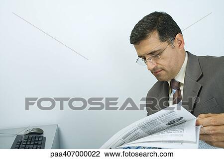 Stock Image - Businessman looking at newspaper. Fotosearch