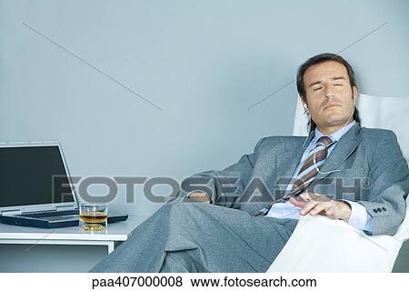Stock Photo - Businessman sitting listening to earphones with eyes closed. Fotosearch