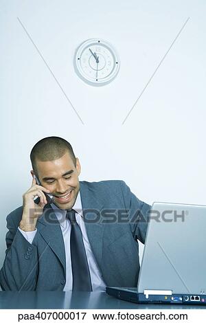 Stock Photo - Businessman using cell phone and laptop. Fotosearch