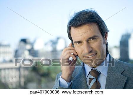 Businessman using cell phone, cityscape in background View Large Photo Image Stock Photograph - Businessman using cell phone, cityscape in background. Fotosearch