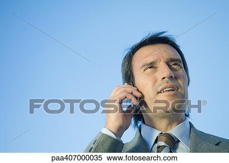 Businessman using cell phone, low angle view View Large Photo Image Stock Photography - Businessman using cell phone, low angle view. Fotosearch