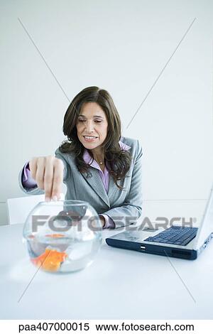 Stock Photography - Businesswoman feeding goldfish. Fotosearch