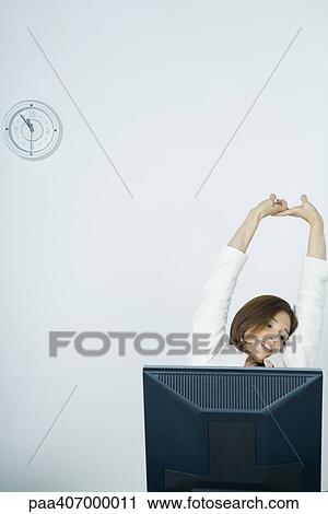 Stock Image - Businesswoman stretching at desk. Fotosearch
