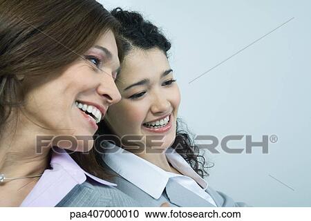 Two businesswomen sitting head to head, smiling View Large Photo Image Stock Image - Two businesswomen sitting head to head, smiling. Fotosearch
