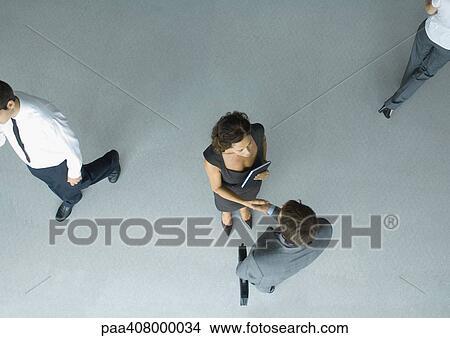 Business associates shaking hands, full length, high angle view View Large Photo Image Picture - Business associates shaking hands, full length, high angle view. Fotosearch