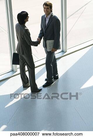 Business associates shaking hands, full length, high angle view View Large Photo Image Stock Photo - Business associates shaking hands, full length, high angle view. Fotosearch