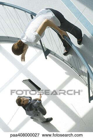 Businessman throwing briefcase up to woman from lower floor, full length, high angle view View Large Photo Image Stock Photo - Businessman throwing briefcase up to woman from lower floor, full length, high angle view. Fotosearch