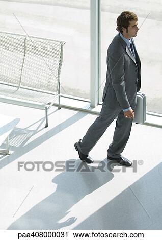 Stock Image - Businessman walking with briefcase, full length, high angle view. Fotosearch