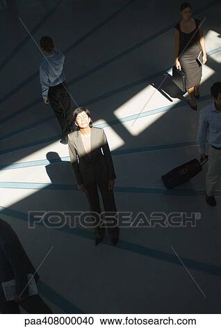 Businesswoman standing with eyes closed in ray of sunlight while people pass by View Large Photo Image Stock Image - Businesswoman standing with eyes closed in ray of sunlight while people pass by. Fotosearch