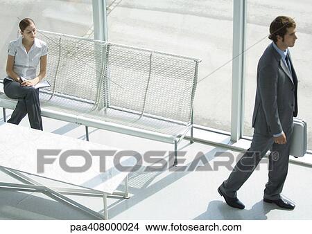 Lobby, woman sitting while businessman passes with briefcase, full length, high angle view View Large Photo Image Picture - Lobby, woman sitting while businessman passes with briefcase, full length, high angle view. Fotosearch