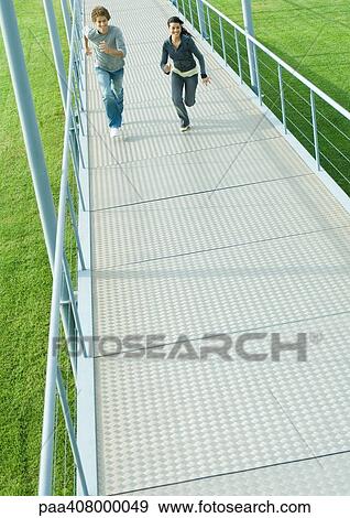 Teenage couple running on walkway, high angle view View Large Photo Image Stock Photo - Teenage couple running on walkway, high angle view. Fotosearch