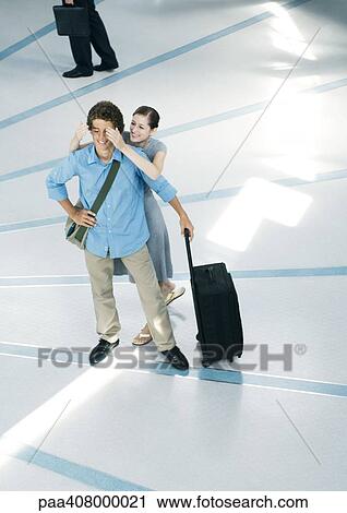 Young woman standing behind male friend, covering eyes, full length, high angle view View Large Photo Image Stock Image - Young woman standing behind male friend, covering eyes, full length, high angle view. Fotosearch
