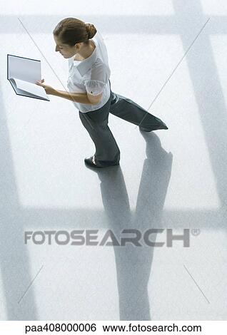 Young woman walking with book, full length, high angle view View Large Photo Image Stock Photograph - Young woman walking with book, full length, high angle view. Fotosearch