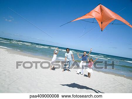 Stock Photo - Family flying kite on beach. Fotosearch