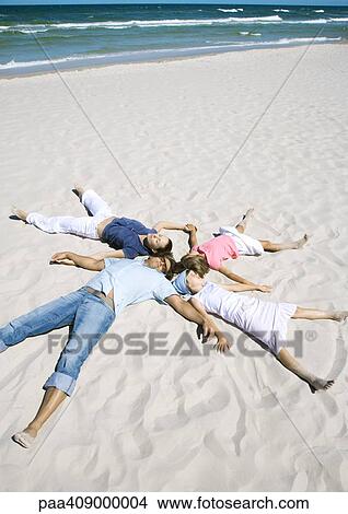 Picture - Family lying on sand, heads together and arms and legs out. Fotosearch