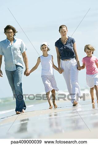 Stock Photo - Family walking hand in hand on beach. Fotosearch