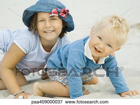 Stock Photo - Girl and toddler boy on beach, smiling at camera. Fotosearch
