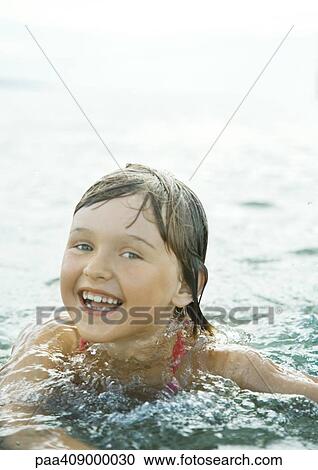 Girl wading in sea, smiling at camera View Large Photo Image Stock Image - Girl wading in sea, smiling at camera. Fotosearch