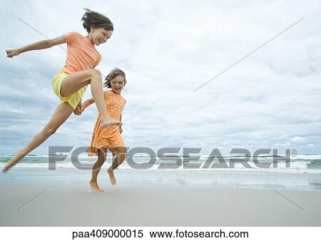 Two girls running and jumping on beach View Large Photo Image Stock Photography - Two girls running and jumping on beach. Fotosearch