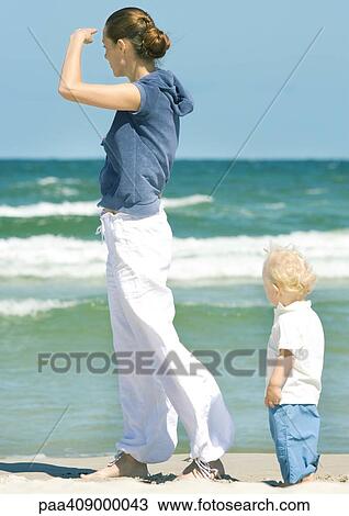 Young woman and toddler standing on beach View Large Photo Image Stock Image - Young woman and toddler standing on beach. Fotosearch