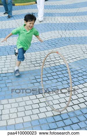 Stock Image - Boy chasing plastic hoop. Fotosearch