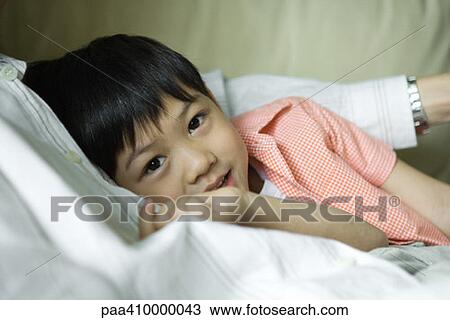 Stock Image - Boy leaning against father, looking at camera. Fotosearch