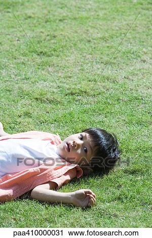 Boy lying on grass View Large Photo Image Stock Image - Boy lying on grass. Fotosearch