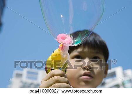 Boy making bubbles with bubble wand View Large Photo Image Stock Photo - Boy making bubbles with bubble wand. Fotosearch