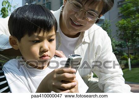 Father and son, boy looking at cell phone View Large Photo Image Stock Photo - Father and son, boy looking at cell phone. Fotosearch