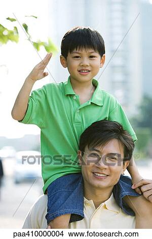 Picture - Man carrying son on shoulders, boy making gesture. Fotosearch