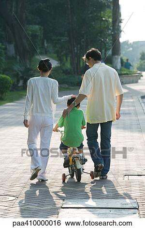 Parents walking next to son on bicycle with training wheels, rear view View Large Photo Image Stock Photograph - Parents walking next to son on bicycle with training wheels, rear view. Fotosearch