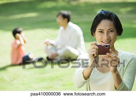 Woman aiming digital camera, smiling at camera View Large Photo Image Stock Photograph - Woman aiming digital camera, smiling at camera. Fotosearch