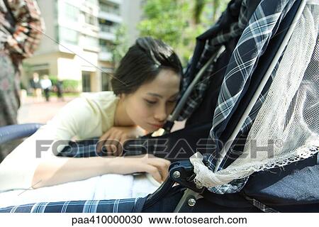Woman crouching by baby carriage View Large Photo Image Stock Image - Woman crouching by baby carriage. Fotosearch