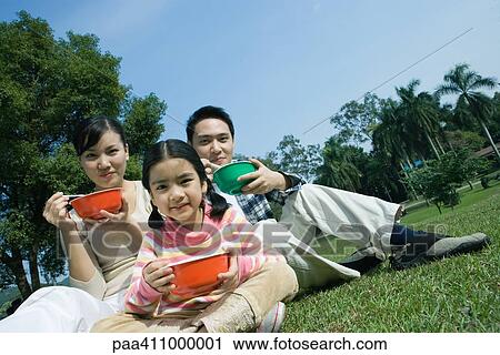 Stock Image - Family eating meal in the park. Fotosearch