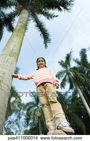 Girl standing next to palm tree, low angle view View Large Photo Image Picture - Girl standing next to palm tree, low angle view. Fotosearch