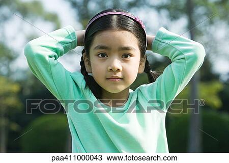 Girl standing with hands behind head, looking at camera View Large Photo Image Stock Image - Girl standing with hands behind head, looking at camera. Fotosearch
