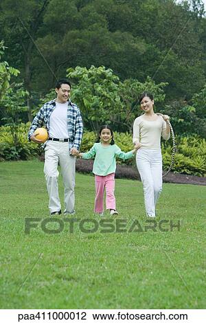 Girl walking across grass with parents View Large Photo Image Stock Image - Girl walking across grass with parents. Fotosearch