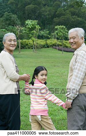 Stock Photography - Girl walking hand in hand with grandparents. Fotosearch
